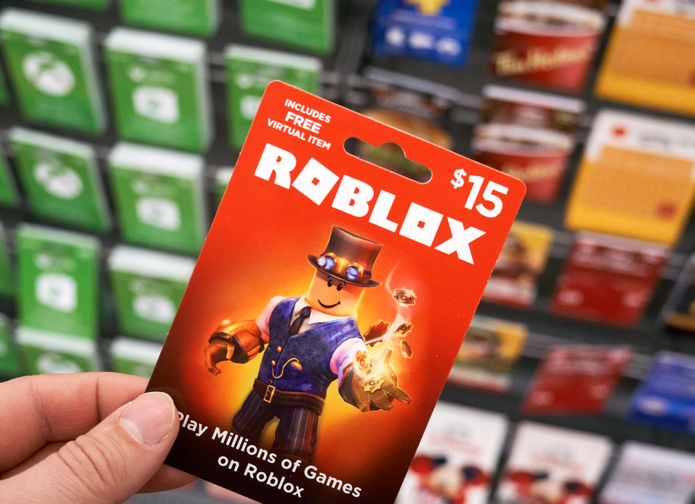 An image of a person's hand holding up a Roblox giftcard, a company which has been sued over mishandling of abuse