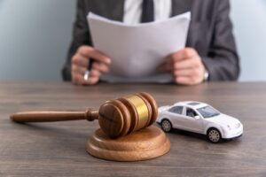 Boston Car Accident Lawyer discussing case strategy with client at desk with gavel and model car
