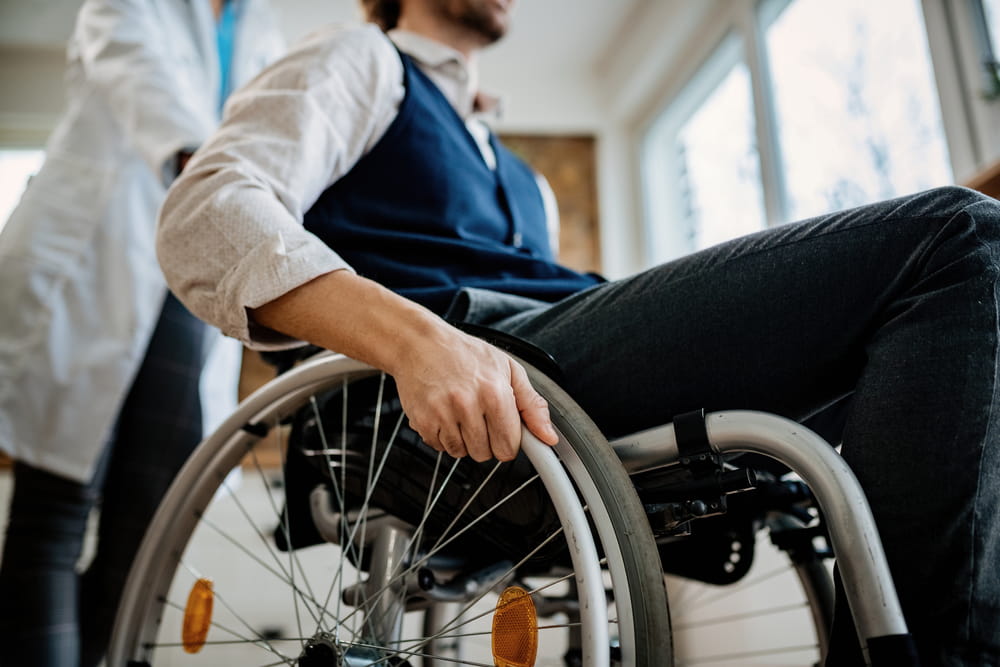 Patient using a wheelchair while being assisted by a healthcare provider during rehabilitation